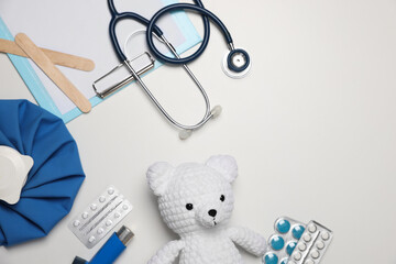 Pediatrics concept. Toy bear with stethoscope, clipboard and pills on white background, flat lay....