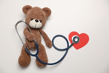 Pediatrics concept. Toy bear with stethoscope on white background, top view