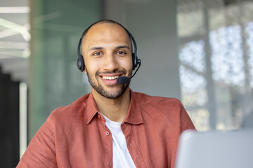 Smiling man wearing a headset, possibly a customer service representative, looking directly at the...