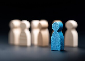 A blue wooden figure, distinct from two groups of identical beige figures, stands alone, symbolizing individuality and difference