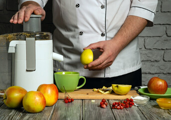 A person in a chef's coat prepares to juice apples and pears in a modern kitchen. Fresh fruits are...