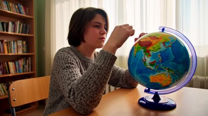 Girl studying a globe in a library - Powered by Adobe