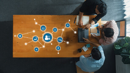 An overhead view of a collaborative team meeting in a modern workspace, featuring technology...