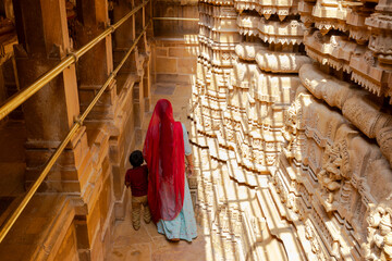 Indian woman dressed in red with his son visiting temple in Jaisalmer (Rajasthan).