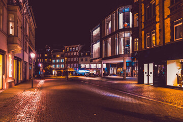 Street scene at night with illuminated shops.