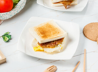 Savory Pork Patty and Egg Toast with Hearty Breakfast Sandwich on Toasted Bread in plate side view...