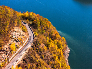 Scenic autumn road winding through vibrant fall foliage and mountains near a lake