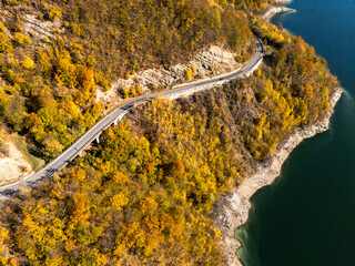 Scenic autumn road winding through vibrant fall foliage and mountains near a lake