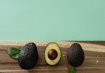 Healthy green horizontal background with three fresh, sliced avocados with sea salt
