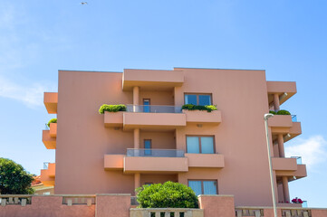 Apartment building exterior. Modern vertical structure with concrete facade, glass balconies,