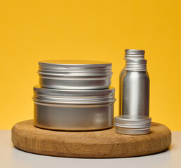 Aluminum jars and bottles for cosmetics and care. Minimalistic packaging on a bright yellow background, branding mockup