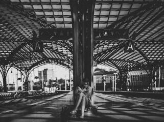 Black and white photo of a train station with striking roof design and one people.