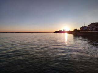 Peaceful sunrise over a wide lake, soft reflections shimmering on the water.