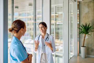 Two female doctors wearing white coats and stethoscopes are discussing a medical diagnosis in a...