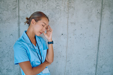 Young female doctor taking a break, experiencing a headache and stress during a difficult workday...