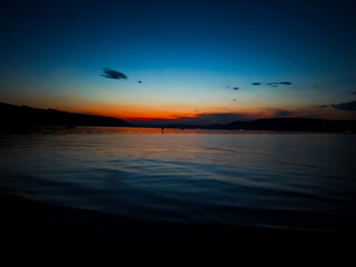 Sunset over calm lake, deep blue tones in the sky and reflection on the water – peaceful evening...