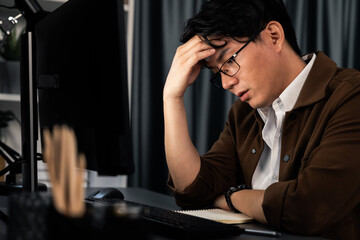 Smart businessman with stressful face working on pc to create business plan report over late night...