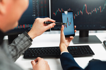 Cropped pointing hand with pen in businessman, checking with holding smartphone by woman investor...