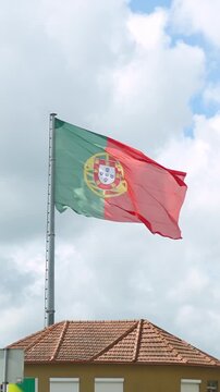 Huge Falg of Portugal blowing in the wind behind a house in 4k footage