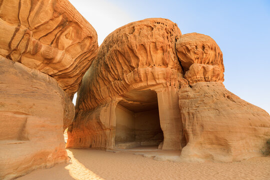 Sunlight illuminating Jabal Ithlib carved facades of ancient Nabataean tombs at Hegra in Al-Ula, Madinah Province, The Diwan and the Siq of a UNESCO World Heritage site in Saudi Arabia