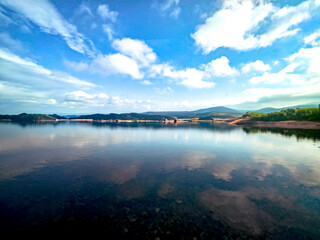 Mirror-smooth lake with cloud reflections under blue sky – peaceful and clear atmosphere.