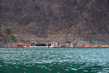 Colorful kayaks and floating dock at Hatta Dam, surrounded by rocky mountains in Hatta