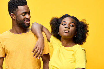Happy young couple in yellow outfits against a vibrant yellow background, showcasing love,...