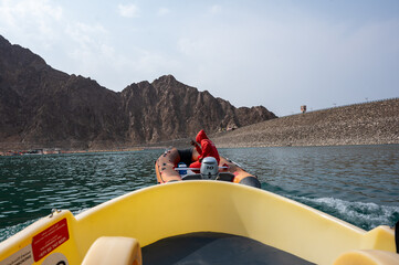 Rescue team assisting on a kayak boat at Hatta Dam, surrounded by rocky mountains and clear blue...