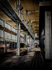 Deep perspective of an abandoned workshop with metal columns and old machinery.