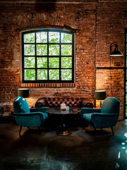 A cozy seating area with a brick wall and large windows in a modern loft with vintage charm.