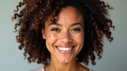 Smiling african female young adult with curly hair against neutral background