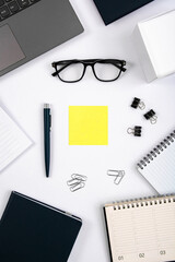 Top view of office table with laptop, pen, nootbook, glasses, stationery and yellow sticky note in home office room, clipping path. Desktop mock up.