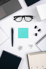 Top view of office table with laptop, pen, nootbook, glasses, stationery and blue sticky note in home office room, clipping path. Desktop mock up.