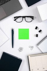 Top view of office table with laptop, pen, nootbook, glasses, stationery and green sticky note in home office room, clipping path. Desktop mock up.