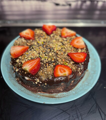 Three chocolates cake with chocolate drips on a black background. Layered cake with milk, black and white chocolate souffle decorated with strawberries on top
