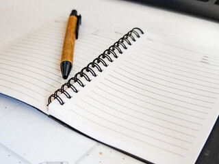 Spiral notebook with lined pages and a brown pen with a black tip &ndash; captured in a close-up.
