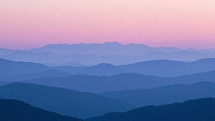 Obraz premium A serene landscape of layered, misty mountains in shades of blue and purple, silhouetted against a soft, gradient sky transitioning from pink at the horizon to a deeper purple above.
