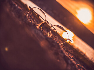 A pair of glasses resting on wood in the warm light of the setting sun – symbolic and calm.