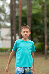a child with dark hair and green eyes is walking in a coniferous forest
