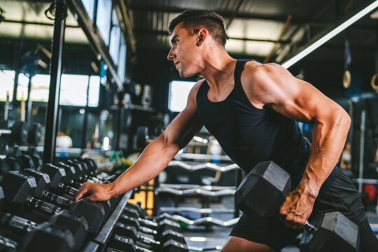 bodybuilder take dumbbell from the shelf and prepare for training