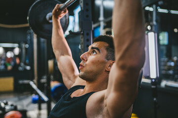 Handsome young athlete man doing bench press workout in gym
