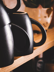 A sleek black ceramic teapot sits on a wooden surface, warmly lit and showcasing its elegant