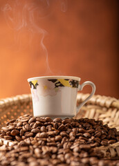 Coffee, beautiful cup of coffee on a heap of coffee beans in a straw sieve, abstract background, selective focus.