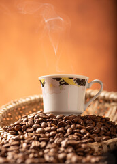 Coffee, beautiful cup of coffee on a heap of coffee beans in a straw sieve, abstract background,...