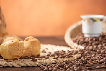Cheese bread and coffee, delicious Brazilian cheese bread and a beautiful cup of coffee on a rustic table and coffee beans, abstract background, selective focus.
