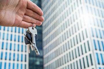 Keys to Success: Hand Holding Keys Against Futuristic Skyscraper. Symbolic image of a hand holding...