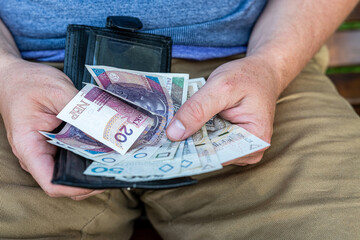 Counting Polish Zloty – Hands of a Man with Wallet and Cash.  A man in casual clothes holding and...