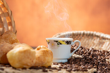 Cheese bread and coffee, delicious Brazilian cheese bread and a beautiful cup of coffee on a rustic table and coffee beans, abstract background, selective focus.