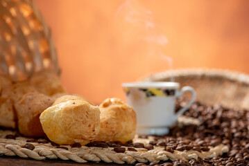 Cheese bread and coffee, delicious Brazilian cheese bread and a beautiful cup of coffee on a rustic table and coffee beans, abstract background, selective focus.