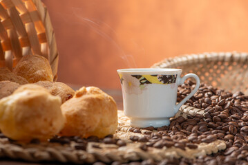 Cheese bread and coffee, delicious Brazilian cheese bread and a beautiful cup of coffee on a rustic table and coffee beans, abstract background, selective focus.